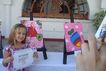 Pequeña artista de 7 años orgullosa con su obra final y su diploma de fin de ciclo